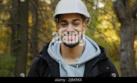 Männlich Porträt jung lächelnd hispanischen professionellen Arbeiter in Schutzhelm posiert im Freien Blick auf Kamera glücklich selbstbewussten Mann Forstingenieur Stockfoto