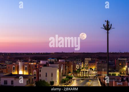 Vollmond über einem purpurnen Himmel in der marokkanischen Stadt Laayoune Stockfoto