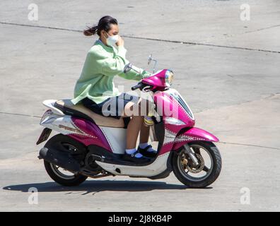 SAMUT PRAKAN, THAILAND, APR 02 2022, Eine Frau mit Gesichtsmaske fährt ein Motorrad Stockfoto