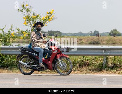 SAMUT PRAKAN, THAILAND, APR 14 2022, Ein Mann mit Gesichtsmaske fährt ein Motorrad auf der Landstraße Stockfoto