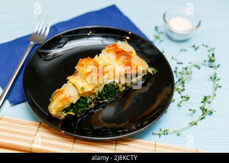 Türkischer nationaler Schneckenteig Kolberegi aus knusprigem Filoteig mit Spinat- und Suluguni-Füllung in saurer Rahm- und Eierkonfitüre Stockfoto