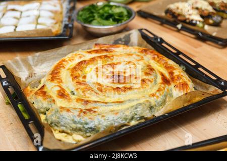 Türkischer nationaler Schneckenteig Kolberegi aus knusprigem Filoteig mit Spinat- und Suluguni-Füllung in saurer Rahm- und Eierkonfitüre Stockfoto