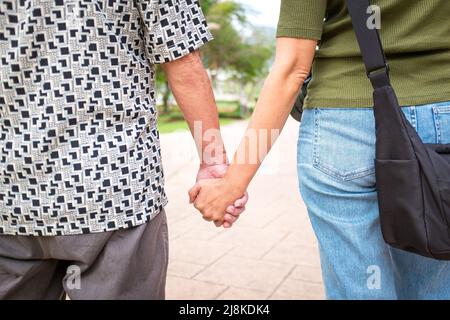 Älterer Mann, Vater und Tochter halten sich beim Spaziergang im Park die Hände. Stockfoto