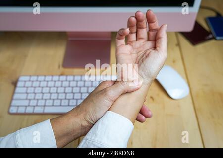 Frau, die ihr Handgelenk reibt, Schmerzen durch die Verwendung der Computermaus. Karpaltunnelsyndrom-Konzept. Nahaufnahme. Stockfoto