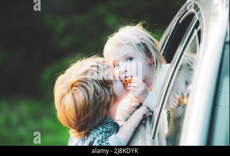 Kleiner Junge gibt Kuss für nettes Mädchen. Auf Wiedersehen. Lustiges kleines Paar, das vor der Autofahrt Auf Wiedersehen sagte. Abschiedskindkonzept. Stockfoto