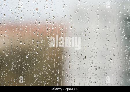 Regentropfen auf einer Fensterscheibe bei regnerischem Wetter Stockfoto