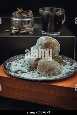 Grüner Tee und Daifuku aus roten Bohnen mit Schmetterlingserbsentee auf dunklem Hintergrund. Japanischer traditioneller Snack, Kopierraum, selektiver Fokus. Stockfoto