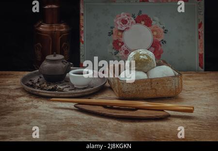 Grüner Tee und Daifuku aus roten Bohnen mit chinesischem Tee auf altem Holzhintergrund. Japanischer traditioneller Snack, selektiver Fokus. Stockfoto