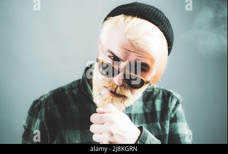 Mann raucht. Nahaufnahme eines jungen Mannes ohne Emotionen. Portrait hübscher Geschäftsmann mit selbstbewusster Gesichts. Stockfoto