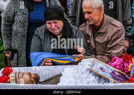 Balabyne, Ukraine. 13.. Mai 2022. (ANMERKUNG DER REDAKTION: Das Bild zeigt den Tod) die Eltern des Sergej Titow, Sergeant der Nationalgarde der Ukraine, der durch russische Schüsse in Orichiv getötet wurde, sitzen an seinem Sarg auf dem Friedhof von Balabyne, Region Saporischschja. Russland marschierte am 24. Februar 2022 in die Ukraine ein und löste damit den größten militärischen Angriff in Europa seit dem Zweiten Weltkrieg aus (Bild: © Rick Mave/SOPA Images via ZUMA Press Wire) Stockfoto