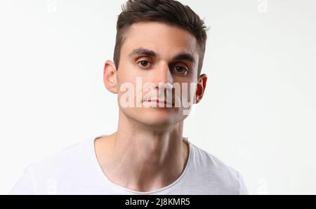 Junger Mann mit ernstem Blick, Brünette Mann Pose auf weißem Hintergrund Stockfoto