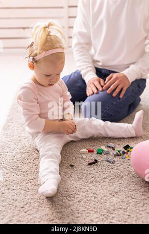 Baby mit Cochlea-Implantaten spielt mit ihrer Mutter und ihrem Vater zu Hause. Stockfoto