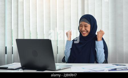 Die muslimische Frau tut einen glücklichen Ausdruck, wenn sie ihre Ziele erreicht. Stockfoto