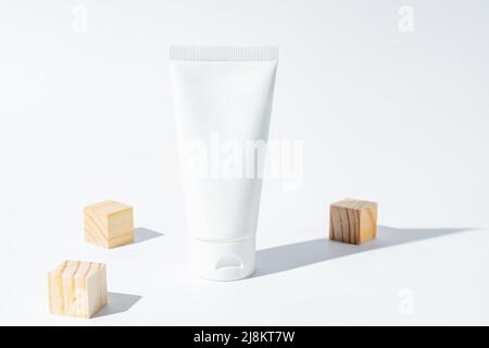 Beauty Spa medizinische kosmetische Lotion Creme in Tube Flasche Verpackung auf weißem Hintergrund mit Sommersaison Sonnenlicht und verstreuten Holzwürfel. Stockfoto