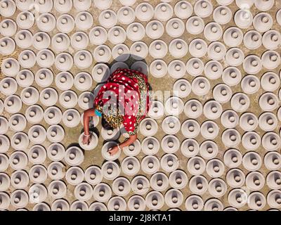 17. Mai 2022, Brahmanbaria, Chittagong, Bangladesch: Woman arrangiert tausende Tontöpfe, bevor sie auf einen Markt in Brahmanbaria, Bangladesch, transportiert wird. Die Tontöpfe werden zum Trocknen unter dem brennenden Sonnenschein ausgelegt, bevor sie als Töpferei in Brennöfen geladen werden. Hier werden täglich rund 3.000 Tontöpfe hergestellt und jeder von ihnen wird für 2 Dollar (2 Dollar) verkauft. Die Töpferei, ein uralter Handel, wird nur von den Menschen der 'Pal'-Gemeinschaft (Potters Community) des Hinduismus betrieben. Seit Jahrhunderten leben sie von ihren Töpferkünsten. Auch heute noch sind ihre Töpfe aus Stockfoto