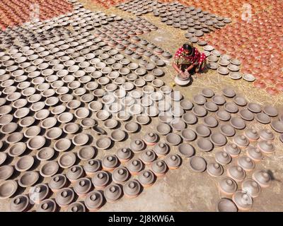 17. Mai 2022, Brahmanbaria, Chittagong, Bangladesch: Frau stellt Tontöpfe her, um sie auf einem Markt in Brahmanbaria, Bangladesch, zu verkaufen. Die Tontöpfe werden zum Trocknen unter dem brennenden Sonnenschein ausgelegt, bevor sie als Töpferei in Brennöfen geladen werden. Hier werden täglich rund 3.000 Tontöpfe hergestellt und jeder von ihnen wird für 2 Dollar (2 Dollar) verkauft. Die Töpferei, ein uralter Handel, wird nur von den Menschen der 'Pal'-Gemeinschaft (Potters Community) des Hinduismus betrieben. Seit Jahrhunderten leben sie von ihren Töpferkünsten. Noch heute sind ihre Töpfe in ganz Bangladesch von enormer Nachfrage. Der Arbeitsauftrag Stockfoto