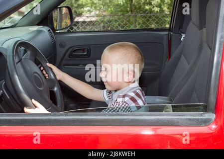 Junge im Auto sitzen, wie der Fahrer das Lenkrad Auto hält Stockfoto