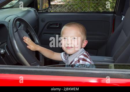 Kleiner Junge, der ein Auto fährt und glücklich sitzt Stockfoto