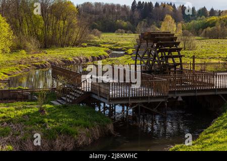 Hölzerne Wassermühle auf einem kleinen gewundenen Fluss. Stockfoto