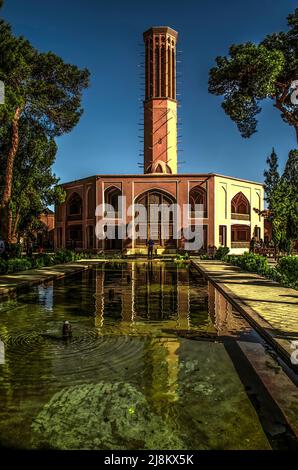 Yazd, Mehriz, Iran, 19. Februar 2021: Ein einzigartiger Bewässerungskanal und Blick auf das Dovlat Abad Sommerpalastgebäude mit Loggien, ovalem Buntglas Stockfoto