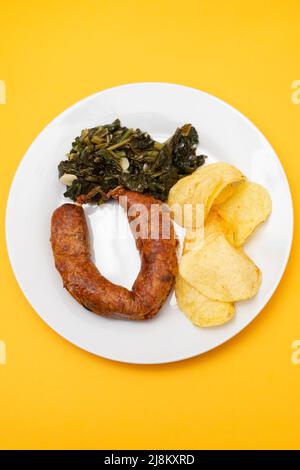 Gebratene typisch portugiesische Räucherwurst mit Pommes Frites und Spinat Stockfoto