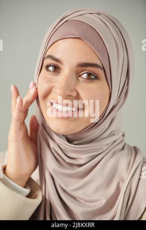 Vertikale Nahaufnahme Kopf- und Schulterporträt einer schönen jungen Frau mit blassrosa Kopfbedeckung und lächelndem Lächeln auf die Kamera Stockfoto