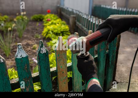 Schleifen und Vorbereiten eines Holzzauns zum Lackieren. Die Hände des Meisters aus der Nähe. Hochwertige Fotos Stockfoto