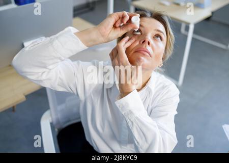 Geschäftsfrau mit Augentropfen. Konzept der Berufskrankheit Stockfoto