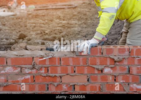 Maurerwerk, das Ziegelsteine auf Mörtel auf dem neuen Wohnhausbau verlegt Stockfoto