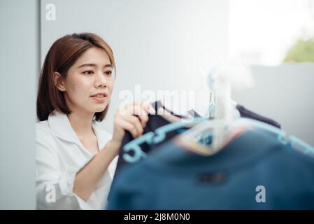 Eine asiatische Hausfrau trocknet nach dem Waschen Kleidung auf dem Regal. Stockfoto