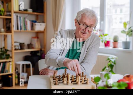 Älterer Mann, der zu Hause ein Schach spielt. Stockfoto