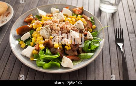 Salatplatte mit Thunfisch, Mais, Tomaten und Rucola Stockfoto