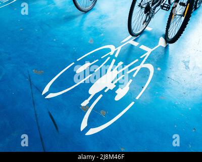 Fahrradparkplatz mit Fahrrad-Piktogramm-Symbol auf dem Boden und Rädern im Hintergrund Stockfoto