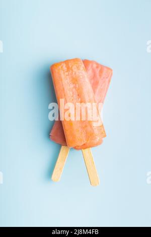 Fruchtiges Eis lolly. Süßes Fruchteis auf einem blauen Tisch. Draufsicht. Stockfoto