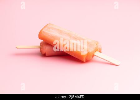 Fruchtiges Eis lolly. Süßes Fruchteis auf einem rosafarbenen Tisch. Stockfoto