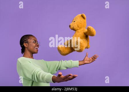 Profil Seitenbild der überglücklich aufgeregt Dame fangen niedlichen plüschtier Teddybär isoliert auf violettem Hintergrund Stockfoto