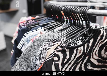 Vintage-T-Shirts und Blusen an Kleiderbügeln aus zweiter Hand Stockfoto