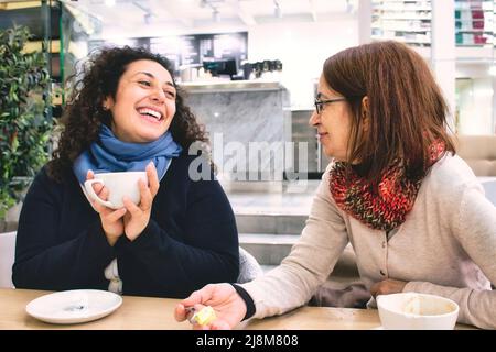 Zwei Frauen verschiedener Generationen genießen eine Tasse Kaffee in einer Cafeteria Stockfoto