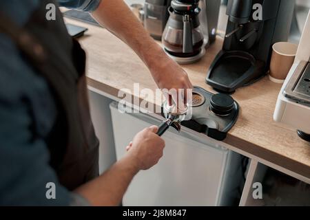 Nahaufnahme des Baristas, der gemahlenen Kaffee zum Espressokochen eintampft Stockfoto