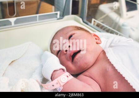 Neugeborenes Mädchen, das gerade im Krankenhaus auf der Entbindungsstation mit einem Plastikschild am Handgelenk geboren wurde Stockfoto