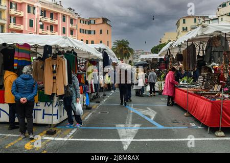 Wochenmarkt auf dem Eroi Sanremesi Platz mit Menschen, die an Regentagen an Kleiderständen einkaufen, Sanremo, Imperia, Ligurien, Italien Stockfoto