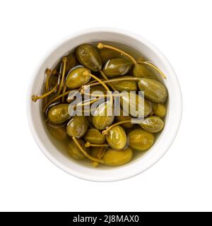 Eingelegte Kaperbeeren in einer weißen Schale isoliert auf weißem Hintergrund. Marinierte Früchte des Kaperbusches. Caperberry aus der Dose zum Würzen und Garnieren. Stockfoto