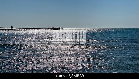 Holzbrücke zum Meer Blendung auf dem blauen Meerwasser. Sandstrand Stockfoto
