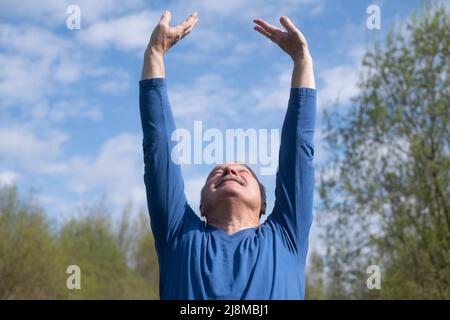 Seniorläufer mit Armreif beim Stretching. Frühling Natur. Gesunde Lebensweise im Alter. Stockfoto