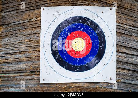 Nahaufnahme eines Bogenschießens, das Zielpapier mit vielen Löchern schießt. Bullseye in Bogen und Pfeil Schießstand Stockfoto