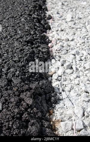 Schicht aus frischem schwarzem Asphalt auf grauem Kies Stockfoto