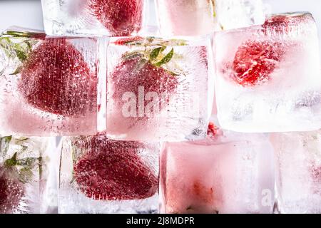 Frische Erdbeeren in Eiswürfeln gefroren - Nahaufnahme. Stockfoto