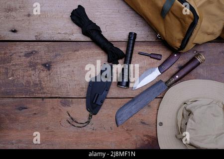 Ein Messer mit Ausrüstung für das Überleben im Wald auf einem alten Holzboden Stockfoto