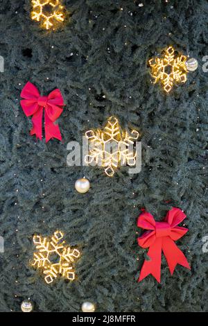 Weihnachtsbaum mit roten Schleifen, Girlanden und Schneeflocken geschmückt. Vollbildfoto. Elegante, nicht nahtlose Textur. Urlaubspostkarte. Stockfoto