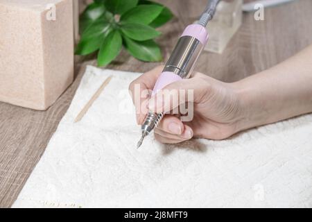 Manikuristin Frau mit Nagelmaschine, verwendet elektrische Nagelbohrmaschine im Schönheitssalon. Hardware-Maniküre. Maniküre oder Operation Nahaufnahme. Stockfoto